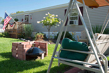 Exterior of a manufactured home, with firepit and swing