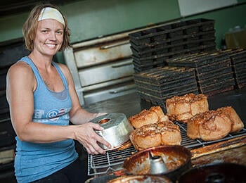 Woman taking bread out of an oven
