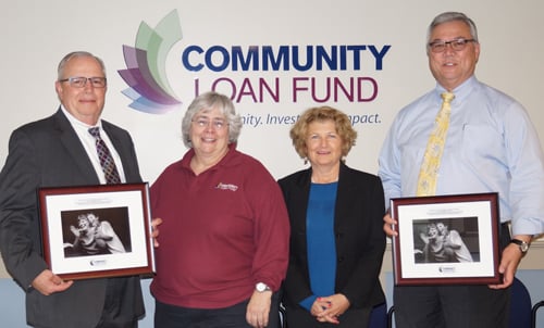 Two men and two women pose in front of Community Loan Fund logo